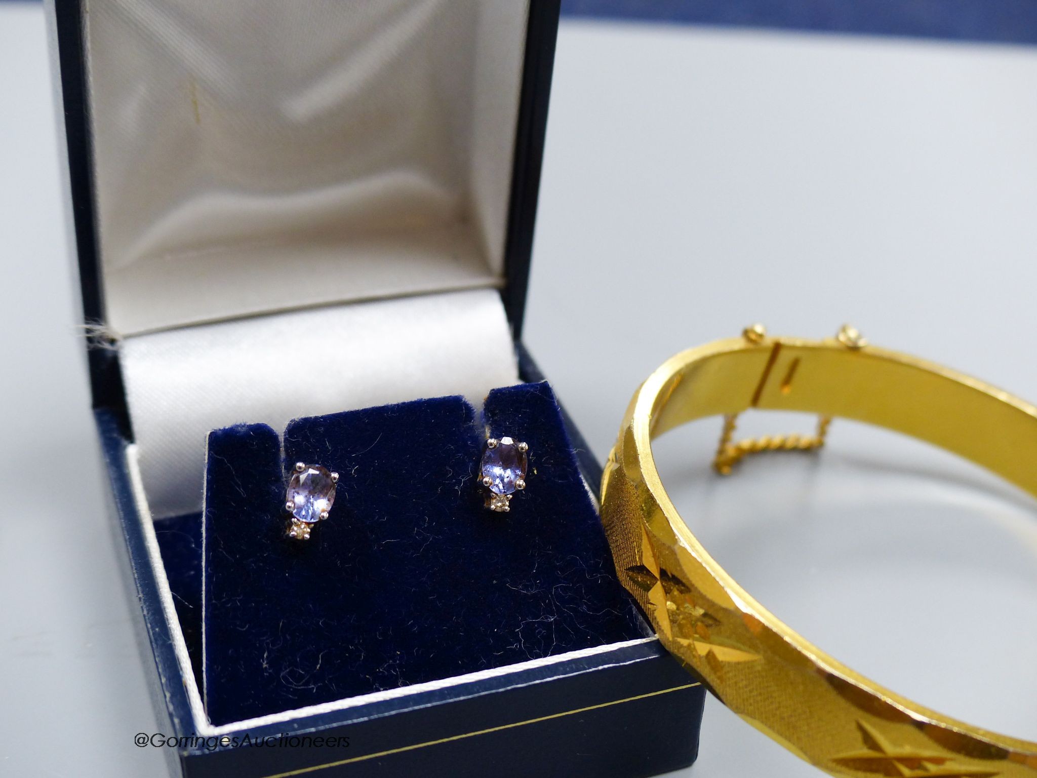 An 18K engraved gold filled hinged bangle and a pair of 14K white metal stud earrings